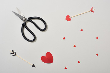 Top view of arrows, scissors and paper hearts on grey background