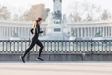 Woman running in the Retiro park in Madrid by a lake. Sport