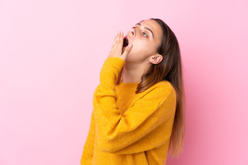 Teenager girl with yellow sweater over isolated pink background yawning and covering wide open mouth with hand