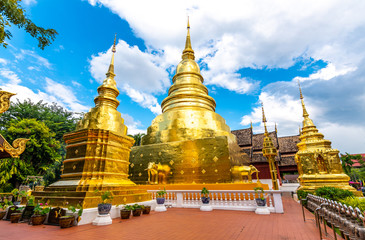 Naklejka premium Beautiful view of Wat Phra Singh temple with golden chedi stupa and pagoda in Chiang Mai city, Thailand. Symbol of buddhism and ancient spirituality. Famous tourist destination. Summer weather