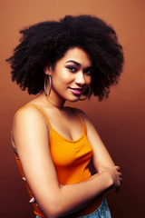 pretty young african american woman with curly hair posing cheerful gesturing on brown background, lifestyle people concept