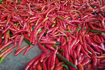 Many spicy red chili peppers on table