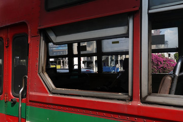 Close up image of old red and green bus with window open.