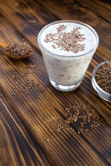 Yogurt or kefir with flax seeds in the glass on the brown wooden  background. Location vertical. Copy space.