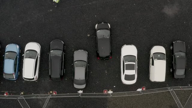 Aerial view above car reverse parking into empty space parking bay.