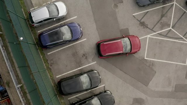 Aerial view birds eye above vehicle reverse parking into empty car parking space.
