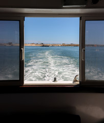 Illustrative image of a boat moving away from Fuseta island in the Algarve. View from inside the boat, water stirred by the boat's propellers.