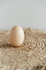 minimalism, one chicken egg on a light background and a straw napkin