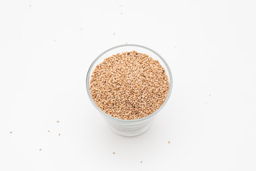 Sesame seeds in glass cup on a white