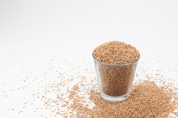 Sesame seeds in glass cup on a white