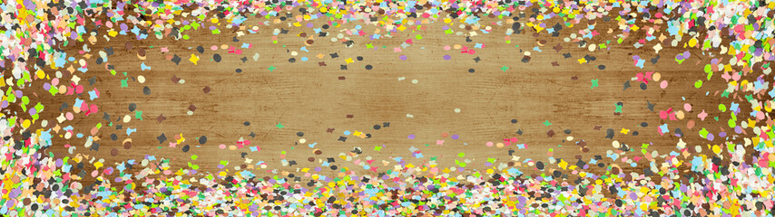 Carnival background panorama banner long - Colorful confetti isolated on brown wooden texture, top view with space for text