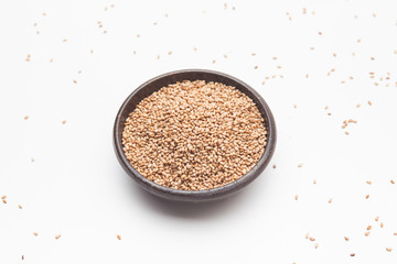 Toasted sesame seeds in crock bowl on white 