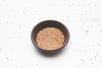 Toasted sesame seeds in crock bowl on white 