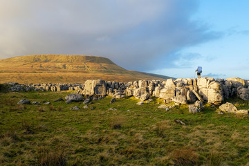Backpacker taking in the view of Ingleborough covered in warm evening light.