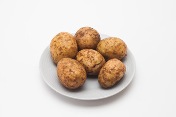 Fototapeta premium Raw potatoes in plate isolated