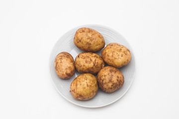 Fototapeta premium Raw potatoes in plate isolated