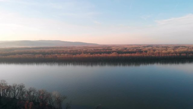 An Aerial Drone Shot of the Danube River in Eastern Europe Looking Out Towards the Horizon in the Evening as the Sun Sets