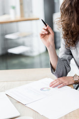 cropped view of account manager sitting at table and holding pen
