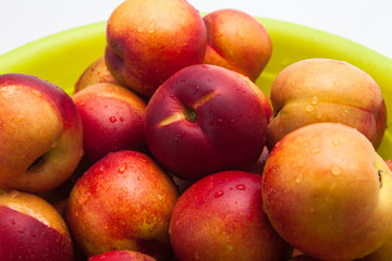 Ripe peaches in a green basket on a white