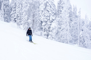 Fototapeta na wymiar Young man in ski suit skiing downhill in mountains during winter vacation
