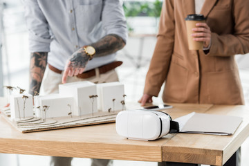 cropped view of virtual reality architects pointing with finger at model of house