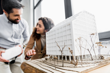 selective focus of model of house and virtual reality architects talking on background