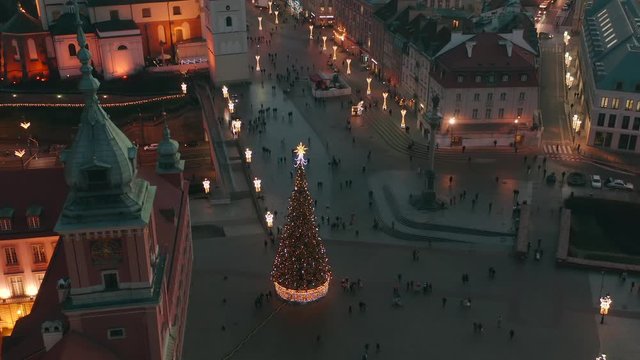 Aerial view of the old city of Warsaw.  Facade of the buildings is beautifully illuminated in the winter at night. Cityscape at dusk overlooking the royal palace and the square with a Christmas tree.