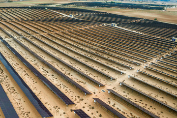 Drone aerial shooting of solar power farm raws of reflective panels. At cloudy day.