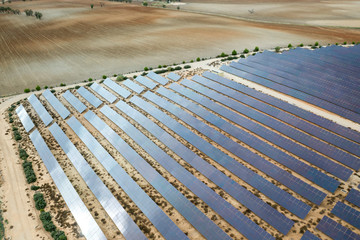 Drone aerial shooting of solar power farm raws of reflective panels. At cloudy day.