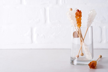 Candy brown and white sugar on a sticks in glass on white background.