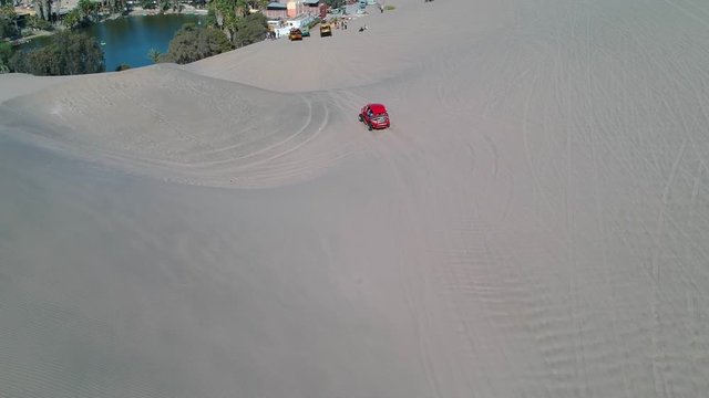 Aerial shot of a red dune buggy at oasis, Huacachina, Peru