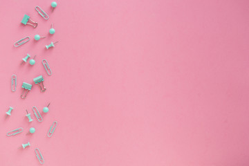 Pink background and green school or office supplies. Flat lay.