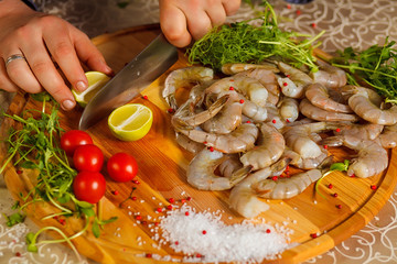 Cook cuts the lime. Close-up. Dish with tiger shrimps, lime and tomatoes.