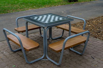 Close-up of a chess table in the park with benches for the players
