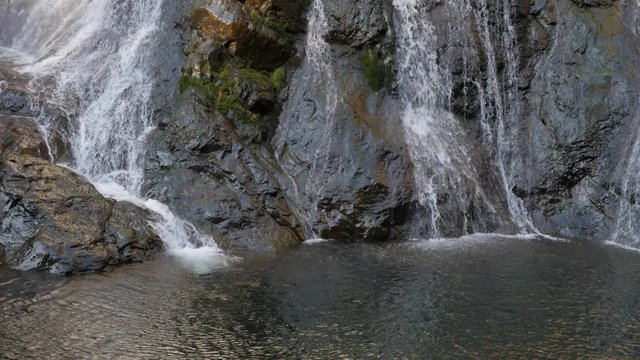 A water fall in nature going down into a natural pool. 