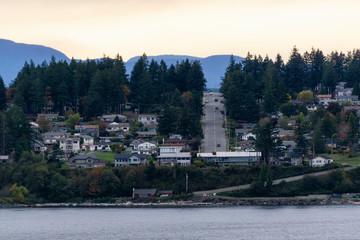 Fototapeta na wymiar Campbell River, Vancouver Island, British Columbia, Canada. Beautiful view of residential homes on the ocean shore during a cloudy evening.