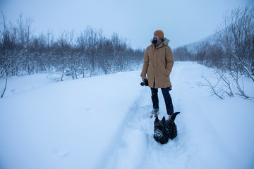 A man photographs his dog on winter walk in the snow