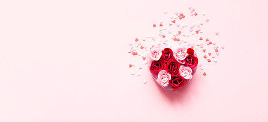 Valentines Day. Heart shape formed of roses flower petals on pink background with sweet confetti. Festive concept. Close-up