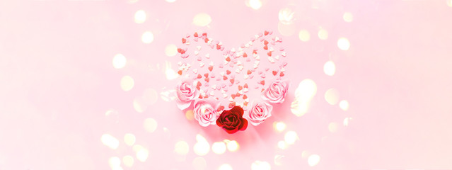 Valentines Day. Heart shape formed of sweet confetti on pink background with rose flower. Template mock up of greeting card or text design. Close-up