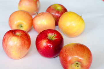 A few fresh red and yellow apples lie on a white background. Selective focus. Close up.