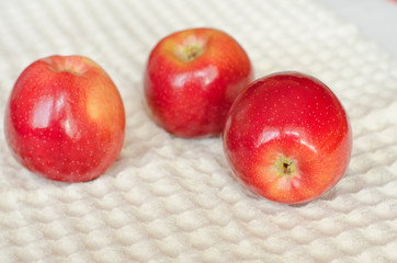 Three fresh red apples lie on a kitchen napkin on a white background. Selective focus. Close up.