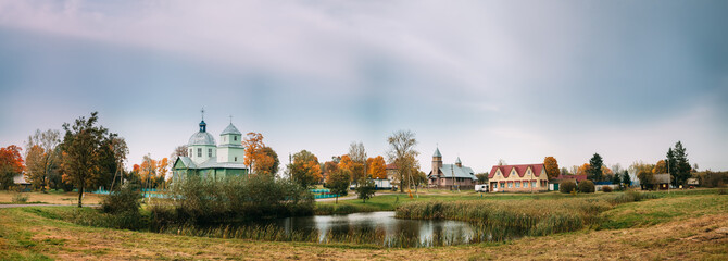 Porplishte, Dokshitsy District ,Vitsebsk Region, Belarus. Old Wooden Church of Transfiguration And Catholic Church Of Virgin Mary In Autumn Day. Panoramic View Panorama