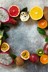 Exotic asia fruit background. Assorted ripe juicy tropical summer seasonal fruits on a gray stone background. Top view flat lay background. Copy space.