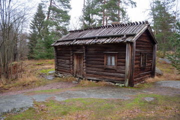 An ancient authentic 18th century wooden house in an autumn forest on the island of Seurasaari in Helsinki, Finland, a cloudy day in late autumn. The harsh beauty of ancient Finland