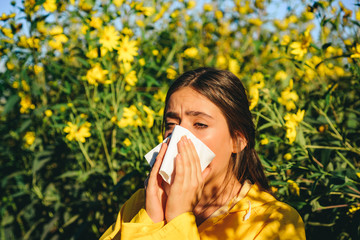Woman with napkin fighting blossom allergie outdoor. Allergy to flowering. Young woman is going to...
