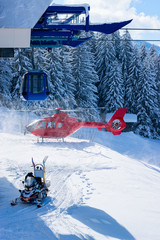 Snowmobile and red helicopter parked cable car station at Zillertal Arena ski resort in Tyrol in...