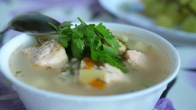 Green Parsley Leaves Fall to Soup with Fish Salmon. Delicious homemade dish in white bowl with spoon. Ingredients, spices and vegetables