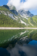 mountain and clouds are reflected in the lake