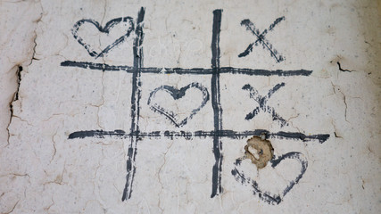Simple game - X-O game.Hand drawn tic-tac-toe elements.Happy Valentines day symbol. Love graphite on old cracked wall.