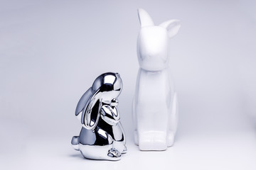 Kleiner silber Hase schaut einen großen weißen Osterhasen an 